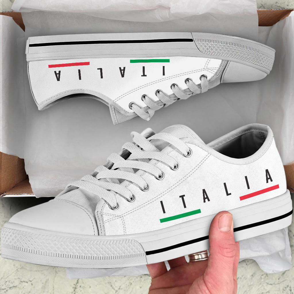 Italy Low-Top Shoes - White in a shoebox with a hand holding one shoe showcasing its design and quality.